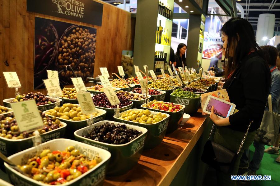 A visitor tastes food at the booth of a Spanish olive company during the 15th International Exhibition of Food & Drink, Hotel, Restaurant & Food Service Equipment, Supplies & Services (HOFEX) in south China's Hong Kong, May 8, 2013. The four-day HOFEX 2013 will last till May 10 at Hong Kong Convention & Exhibition Center. (Xinhua/Li Peng) 