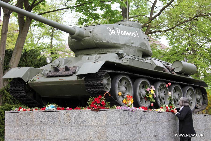 A visitor pays tribute to the Soviet Red Army by laying bouquet at a T-34 Tank model displayed at the German-Russian Museum in Karlshorst, Berlin, Germany, on May, 8, 2013. People from across Europe commemorated on Wednesday, in one way or another, the 68th Victory in Europe Day (VE Day) that marks the end of the Second World War (WWII) in Europe. (Xinhua/Pan Xu)