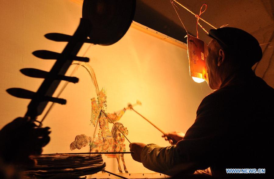 Folk artist Jing Tingxiao, 63 years old, presents Daoqing (a folk operetta originated from the chanting of Taoist scriptures) shadow play backstage at Chenqiyuan Village in Huanxian County, Qingyang, northwest China's Gansu Province, May 8, 2013. Huanxian County, which locates in the east of Gausu Province, boasts its Daoqing shadow play. The art form is popular among local residents for its attractive performance. (Xinhua/Guo Gang)