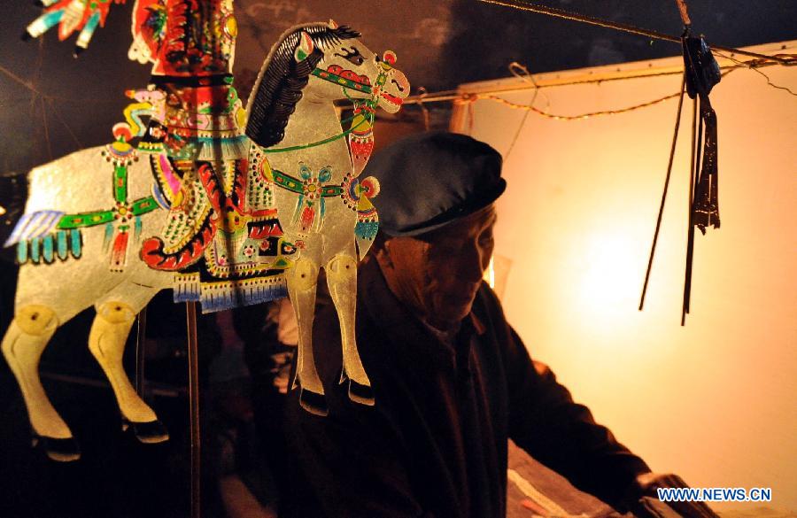 Folk artist Jing Tingxiao, 63 years old, prepares before a Daoqing (a folk operetta originated from the chanting of Taoist scriptures) shadow play backstage at Chenqiyuan Village in Huanxian County, Qingyang, northwest China's Gansu Province, May 8, 2013. Huanxian County, which locates in the east of Gausu Province, boasts its Daoqing shadow play. The art form is popular among local residents for its attractive performance. (Xinhua/Guo Gang) 