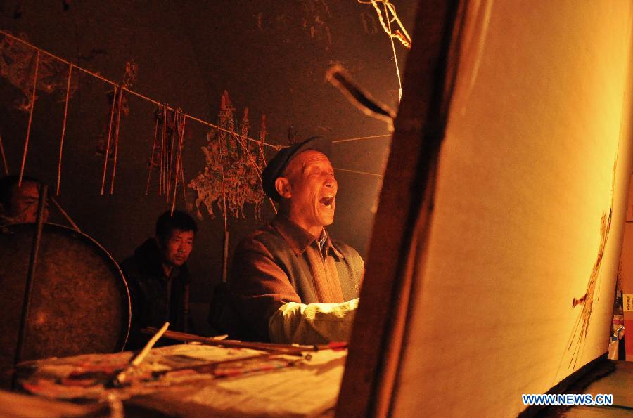 Folk artist Jing Tingxiao, 63 years old, presents Daoqing (a folk operetta originated from the chanting of Taoist scriptures) shadow play backstage at Chenqiyuan Village in Huanxian County, Qingyang, northwest China's Gansu Province, May 8, 2013. Huanxian County, which locates in the east of Gausu Province, boasts its Daoqing shadow play. The art form is popular among local residents for its attractive performance. (Xinhua/Guo Gang) 