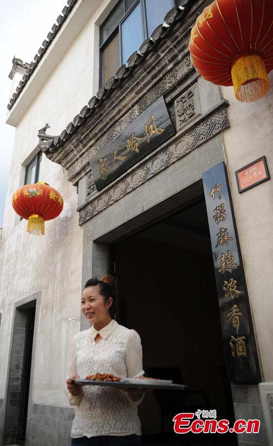 A waitress serves dishes in Baimaguan County, Luojiang, Sichuan Province. Damaged houses in Baimaguan have been restored five years after the Wenchuan earthquake, which transformed the county into a tourist attraction. In 2012, total revenue from tourism reached 186 million yuan. Baimaguan used to be a famous battlefield during the Three Kingdoms period (220 AD-280AD). (CNS/Liu Zhongjun)