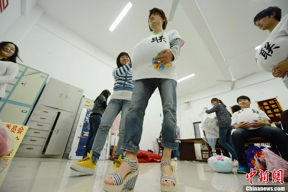 Male college students wear high heels and dress up as pregnant women to experience the hard life of a "mother-to-be" in a celebration of the upcoming Mother's Day in Yangzhou, east China's Jiangsu province, May 9, 2013. They hope this activity will express their best wishes to mothers and "mothers-to be". (Photo/CNS)