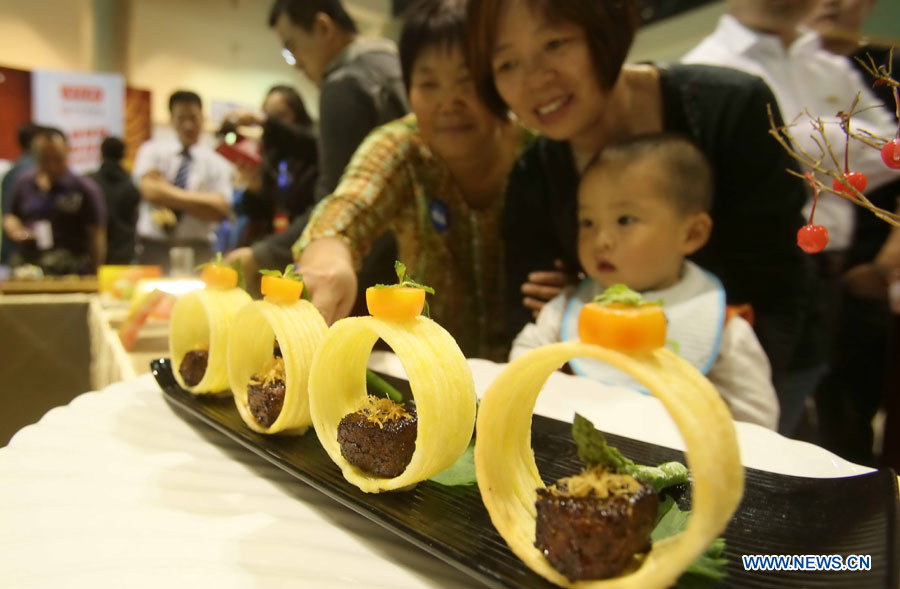 Visitors view a dish during the 8th China (Beijing) Catering & Food Fair in Beijing, capital of China, May 9, 2013. (Xinhua)