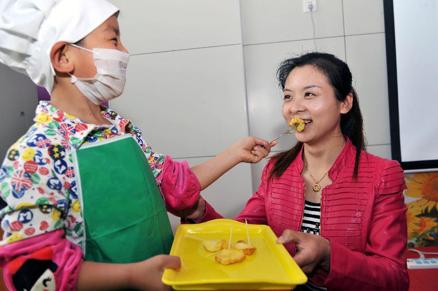 A boy named Feng Zhicheng feeds his mother with the cakes he makes in the Liyuejiayuan kindergarten in the Huaiyin District of Jinan, capital of east China's Shandong Province, May 10, 2013. Children here made cakes and helped make up for their mothers to celebrate the coming Mother's Day. (Xinhua/Zhu Zheng) 