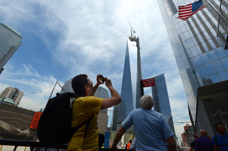 Visitors take photos of One World Trade Center (WTC) in New York, May 10, 2013. Workers have installed the final sections of the silver spire atop WTC on Friday, which brings the iconic New York City structure to its full, symbolic height of 1,776 feet (541 meters). (Xinhua/Wang Lei) 