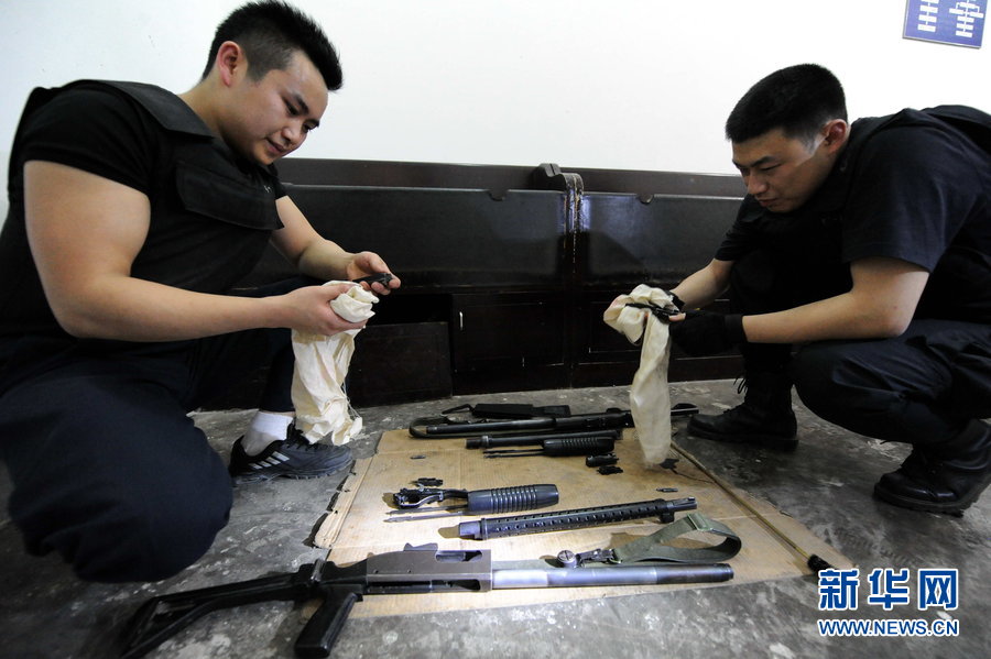 Armed cash transit security guards clean guns before starting an escort mission. (Xinhua Photo)