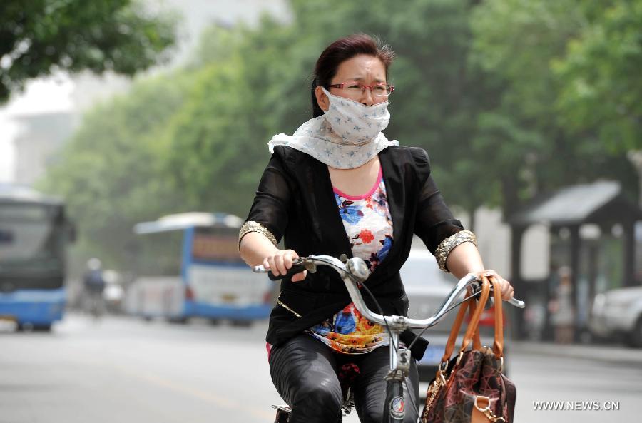 A woman covers her face with a scarf to protect her from floating dust in Yinchuan, capital of northwest China's Ningxia Hui Autonomous Region, May 13, 2013. Floating dust hit Yinchuan on Monday. (Xinhua/Peng Zhaozhi) 