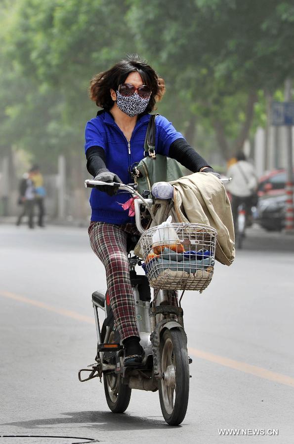 A woman covers her face with a scarf to protect her from floating dust in Yinchuan, capital of northwest China's Ningxia Hui Autonomous Region, May 13, 2013. Floating dust hit Yinchuan on Monday. (Xinhua/Peng Zhaozhi) 