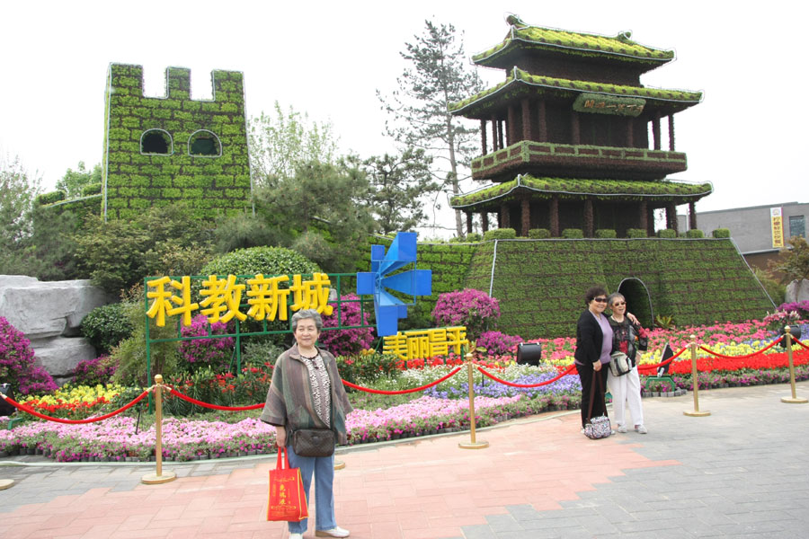 People taking pictures in front of a flower structure featuring Beijing's Changping District in the Ninth China (Beijing) International Garden Expo west of the Yongding River. The expo covers an area of 513 hectares, including 267-hecare public exhibition area and 246-hectare Garden Expo Lake. The event will officially kick off on May 18, 2013 and last for six months. (CRIENGLISH.com/Luo Dan)