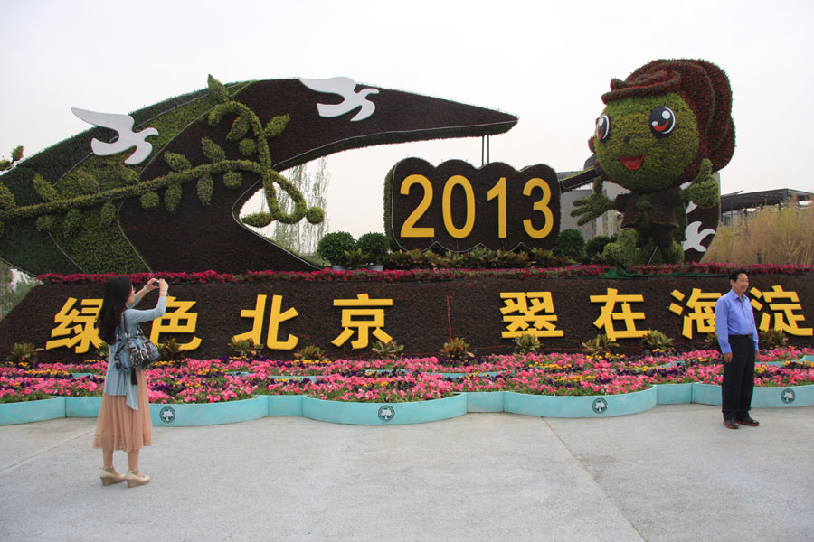 People taking pictures in front of a flower structure featuring Beijing's Haidian District in the Ninth China (Beijing) International Garden Expo west of the Yongding River. The expo covers an area of 513 hectares, including 267-hecare public exhibition area and 246-hectare Garden Expo Lake. The event will officially kick off on May 18, 2013 and last for six months. (CRIENGLISH.com/Luo Dan)