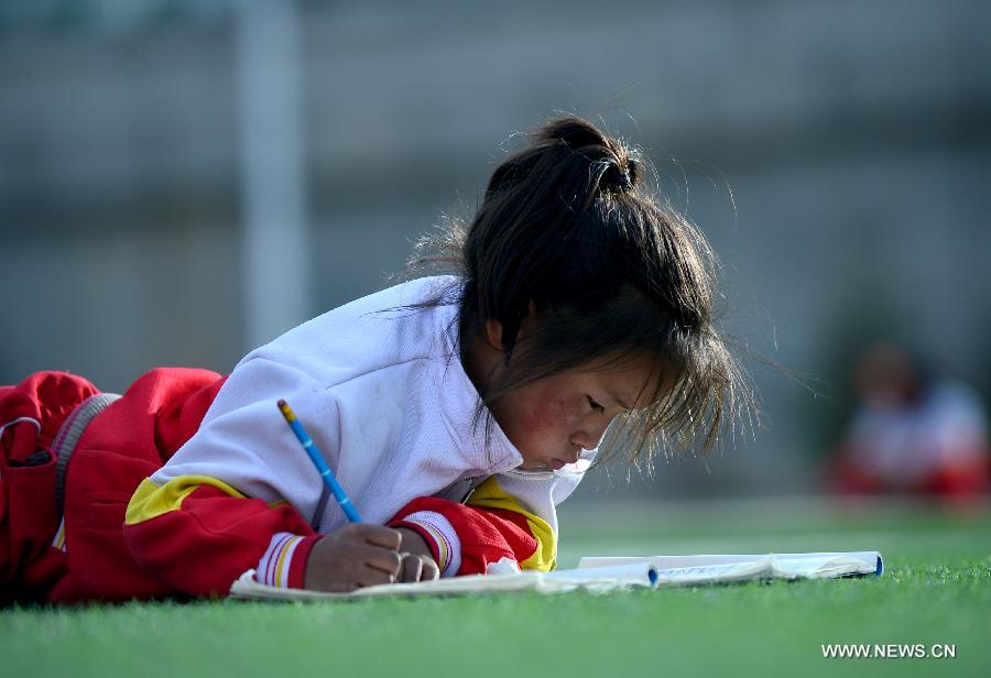 Orphan student Gengga Yongji reads a book at the Bayi Orphan School in Yushu Tibet Autonomous Prefecture in northwest China's Qinghai Province, May 13, 2013. The school is now a home of 323 orphan students who are instructed and cared by 57 teachers. (Xinhua/Wang Bo)