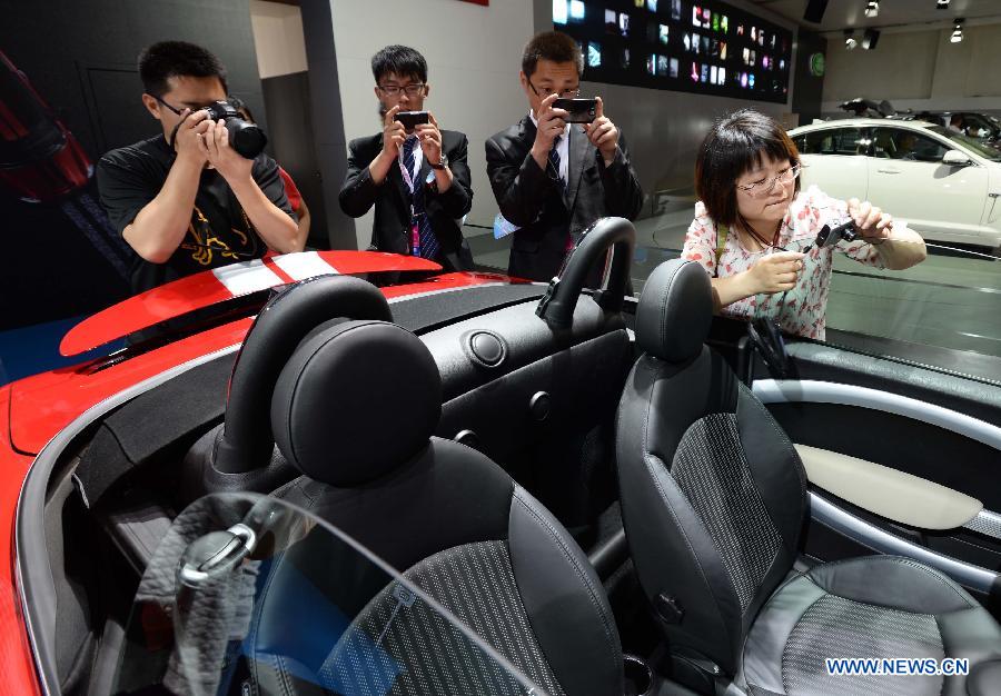 People take pictures of a car at the 2013 Qingdao International Auto Show in Qingdao, a coastal city in east China's Shandong Province, May 14, 2013. The six-day auto show kicked off on Tuesday. (Xinhua/Li Ziheng)