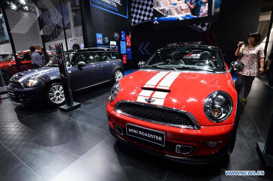 A woman takes pictures of a car at the 2013 Qingdao International Auto Show in Qingdao, a coastal city in east China's Shandong Province, May 14, 2013. The six-day auto show kicked off on Tuesday. (Xinhua/Li Ziheng)