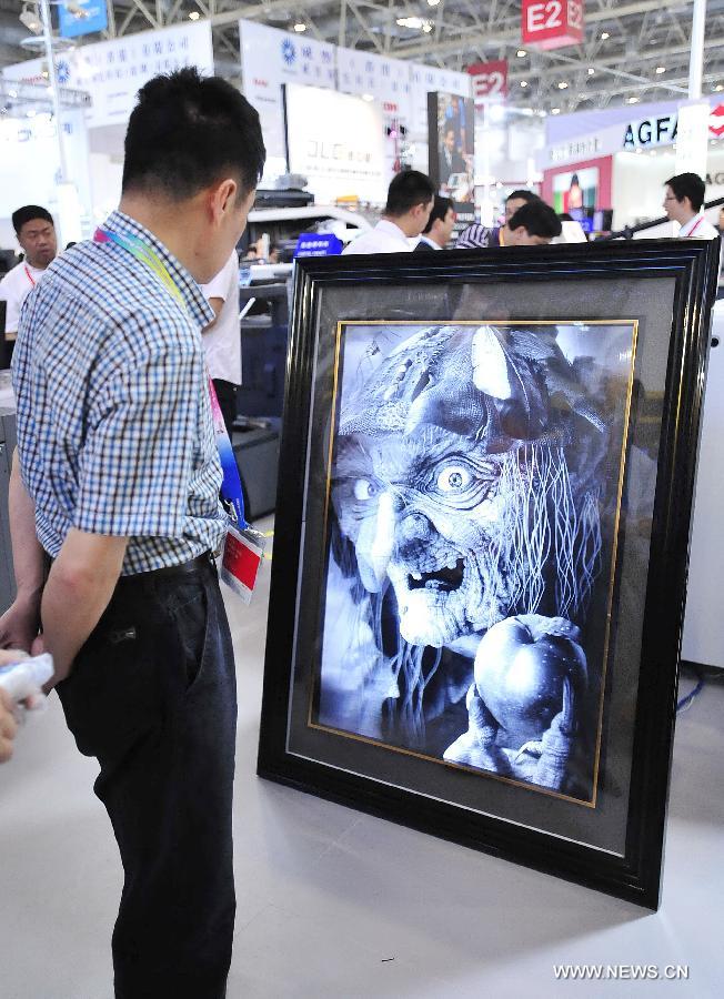 A visitor watches a three-dimensional photo during the 8th Beijing International Printing Technology Exhibition in Beijing, capital of China, May 14, 2013. The five-day exhibition opened at New China International Center in Beijing Tuesday. (Xinhua/Xiao Xiao) 