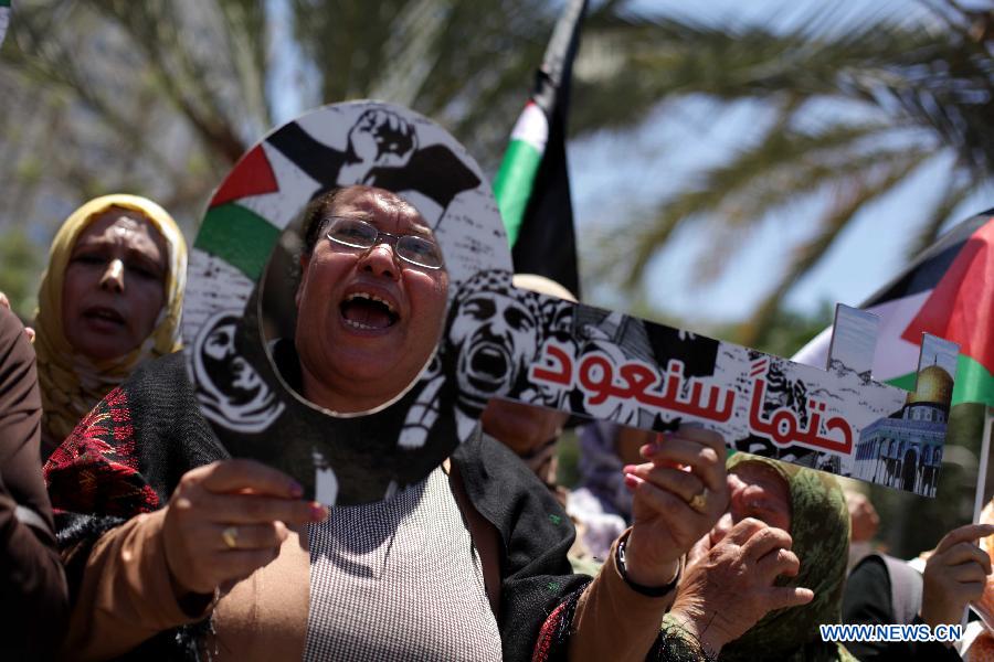 Palestinian protesters take part in a rally ahead of Nakba Day near the border between Israel and the southern Gaza Strip city of Khan Younis on May 14, 2013. Palestinians are preparing to mark Nakba Day on May 15, which marked thousands of Palestinians were forced to leave their homes during the Arab-Israeli war in 1948. (Xinhua/Khaled Omar)