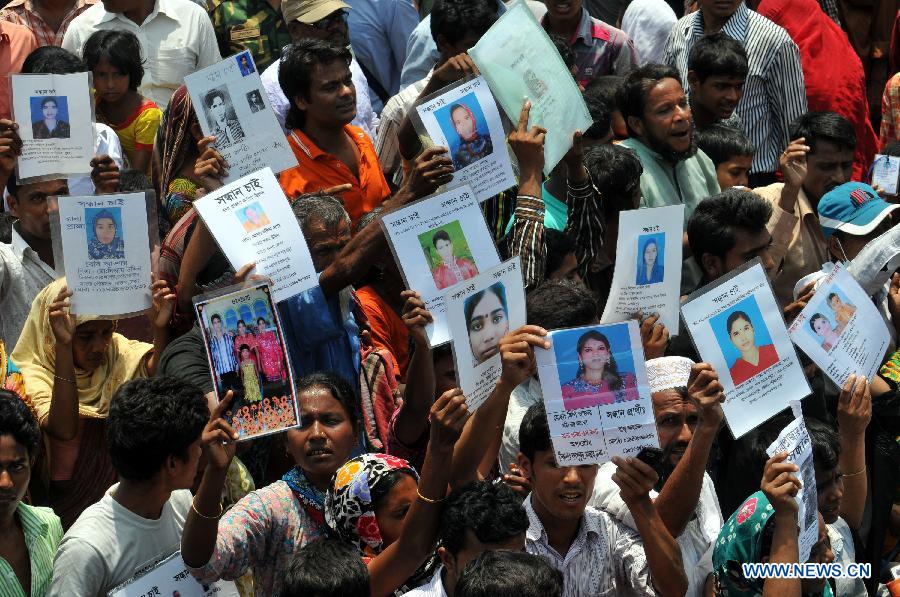 People show photos of their missing relatives in front of the site of collapsed Rana Plaza building in Savar on the outskirts of Dhaka, Bangladesh, May 14, 2013. Twenty days into the collapse of the building when the confirmed death toll stands at 1,127, the rescuers wrapped up their recovery operations Tuesday morning. (Xinhua/Shariful Islam)