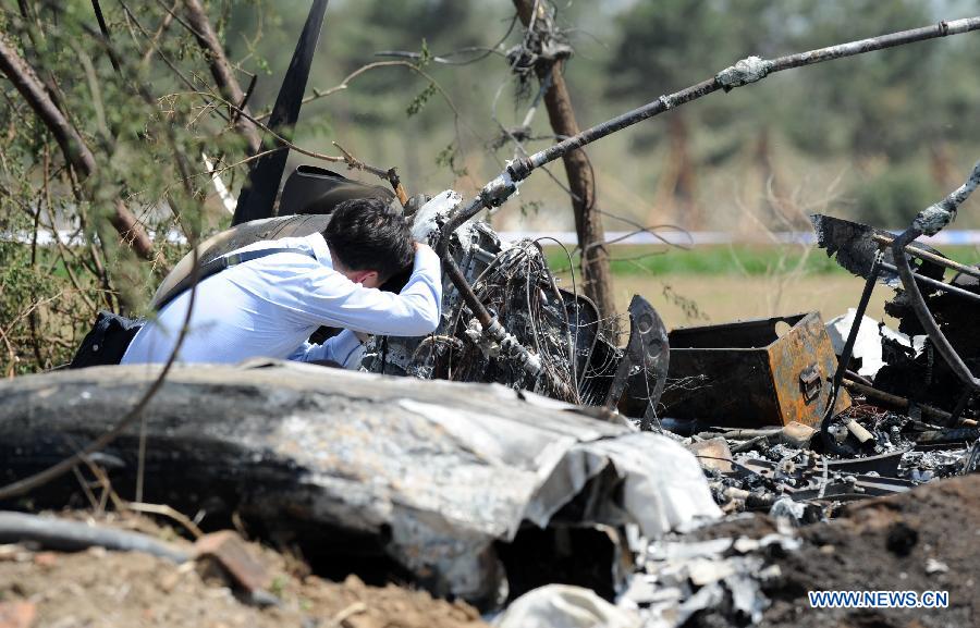 An investigator works beside the remains of a light plane after it failed to take off at Taoxian Airport in Shenyang, capital of northeast China's Liaoning Province, May 16, 2013. Three people on board were injured in the accident on Thursday. (Xinhua/Yang Qing) 