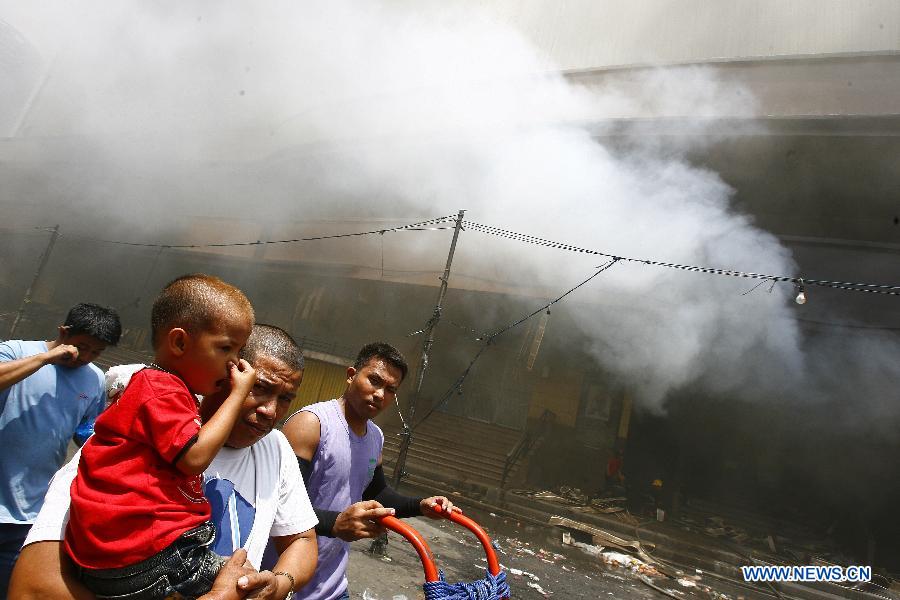 Local people evacuate from the fire accident site in Manila, the Philippines, May 16, 2013. Two people were rescued from the fire, as firefighters estimate the fire may last for two days. (Xinhua/Rouelle Umali) 