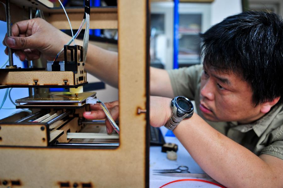 Han Bing adjusts his handmade 3D printer in Tianjin Municipality, north China, May 16, 2013. Based on the method released on the internet, the 41-year-old by himself made this machine eventually, which costing some 2,000 RMB yuan (325 U.S. dollars) and spending four months. At present, Han's 3D printer could only make simple items designed on the computer, like teapots and whistles. And he hopes his creation could function more powerfully by continuous improvement. (Xinhua/Zhang Chaoqun) 