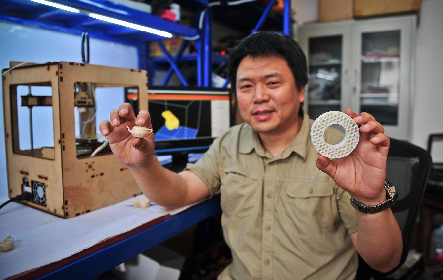 Han Bing shows items made by his handmade 3D printer in Tianjin Municipality, north China, May 16, 2013. Based on the method released on the internet, the 41-year-old by himself made this machine eventually, which costing some 2,000 RMB yuan (325 U.S. dollars) and spending four months. At present, Han's 3D printer could only make simple items designed on the computer, like teapots and whistles. And he hopes his creation could function more powerfully by continuous improvement. (Xinhua/Zhang Chaoqun) 