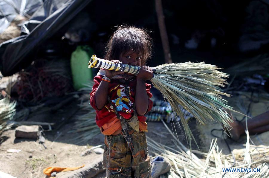 A Hindu child holds a broom at a slum area near Bijbehara town of Anantnag district, around 44 km south of Srinagar city, the summer capital of Indian-controlled Kashmir, May 16, 2013. Thousands of poor Hindu labourers from Indian states migrate to Indian-controlled Kashmir during summers to escape the scorching heat and earn their livelihood by either doing menial jobs or selling brooms. (Xinhua/Javed Dar)