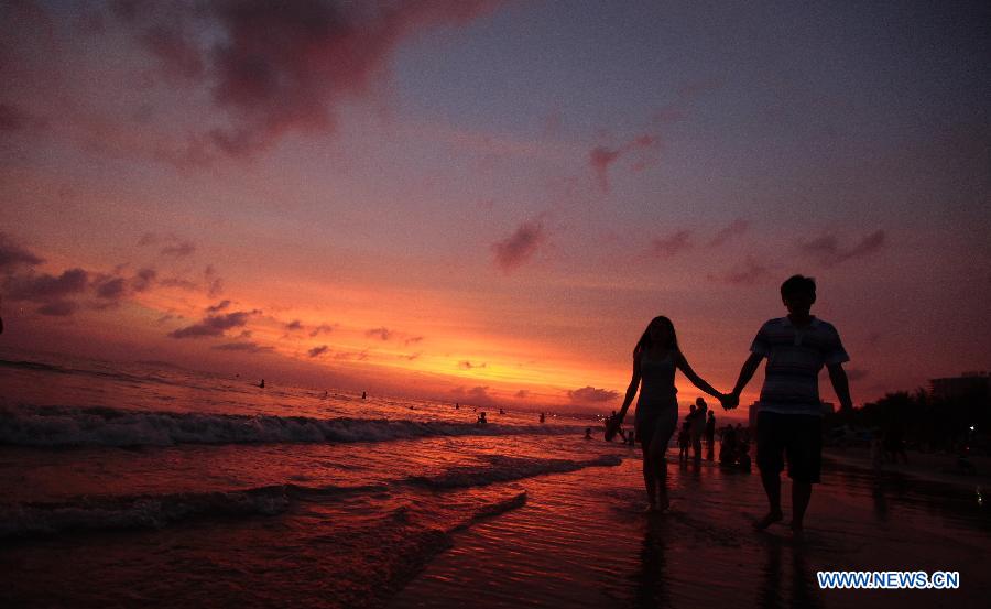 People enjoy themselves on a beach at sunset in Sanya, south China's Hainan Province, May 16, 2013. (Xinhua/Chen Wenwu)  