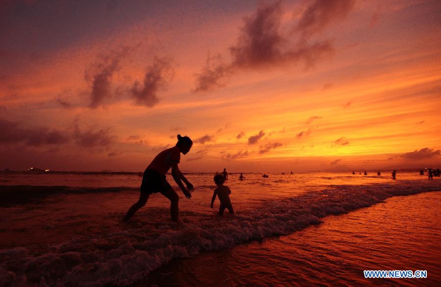 People enjoy themselves on a beach at sunset in Sanya, south China's Hainan Province, May 16, 2013. (Xinhua/Chen Wenwu)  