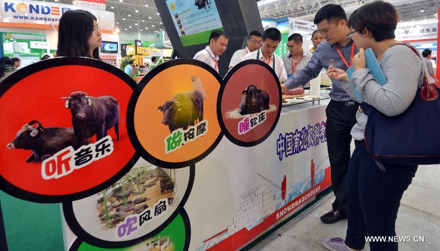 Visitors taste toasted beef at the 11th (2013) China Animal Husbandry Expo in Wuhan, capital of central China's Hubei Province, May 18, 2013. The expo, which kicks off on May 18, will last until May 21. (Xinhua/Hu Weiming)