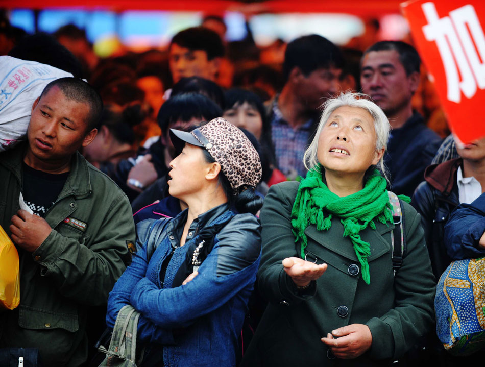 Chen Wanjie feels the rain at the railway station in Suihua of Heilongjiang on May 10, 2013. Chen, 53, from Wankui county of northeast China's Heilongjiang province, will go to transplant rice in Sanjiang plain, east of Heilongjiang Province. The temporary work will last 20 days with a payment of 200 yuan ($28) a day. 