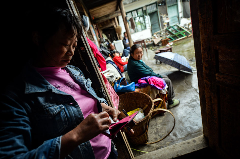 Zhao Siqiong takes out her daughter's identity card from her wallet in Lushan county in Sichuan on May 7, 2013. Her daughter was buried in the ruins after the earthquake. It has been half a month since the Lushan Earthquake, but the pain remains forever. (Xinhua/Bai Yu)