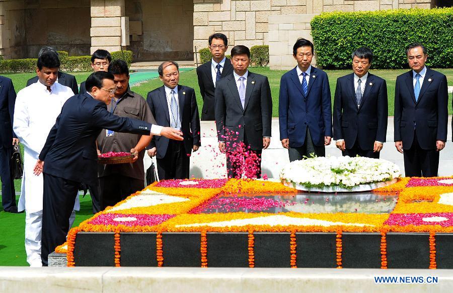 Chinese Premier Li Keqiang (L) scatters petals to the memorial of Mahatma Gandhi after laying a wreath, in New Delhi, India, May 20, 2013. (Xinhua/Li Tao)