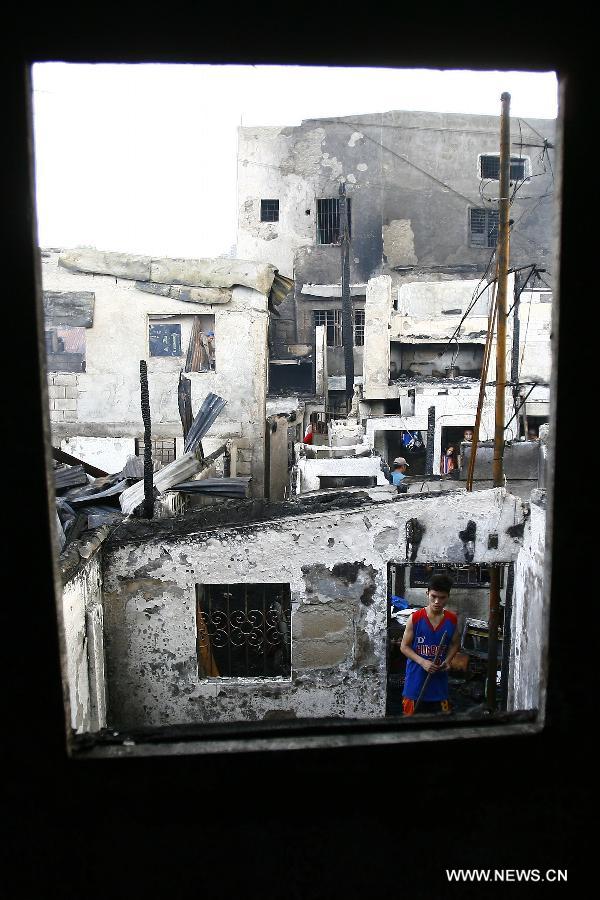 Residents retrieve reusable materials from their burnt homes after a fire razed a residential area in Quezon City, the Philippines, May 21, 2013. More than 200 families were left homeless in the fire. (Xinhua/Rouelle Umali)