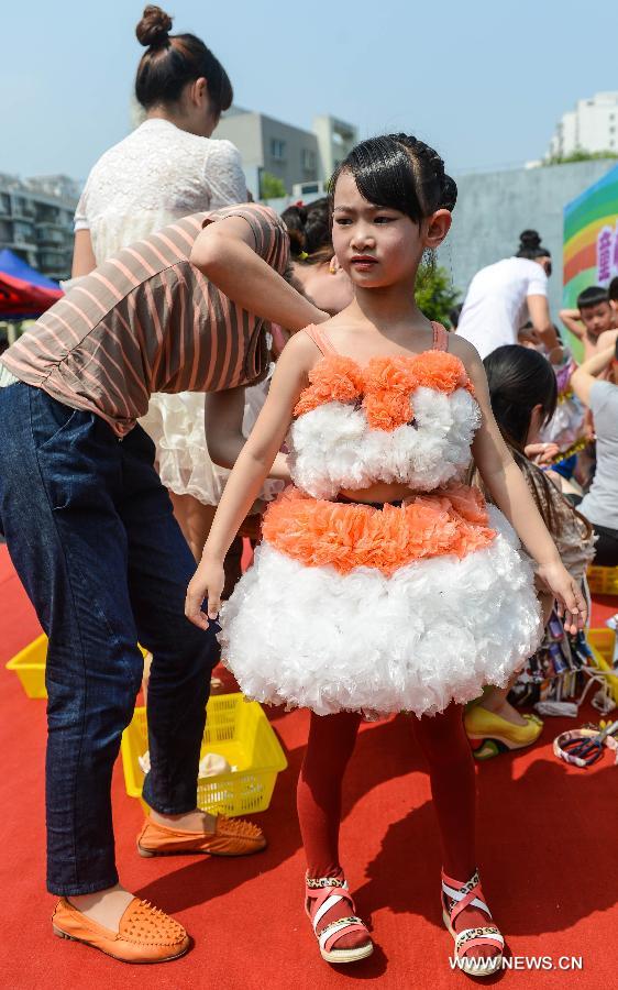A parent helps a girl dress on DIY creations in a kindergarten in Hangzhou, capital of east China's Zhejiang Province, May 21, 2013. An activity for children to present their ideas and creations was held to celebrate the coming Children's Day. (Xinhua/Xu Yu) 
