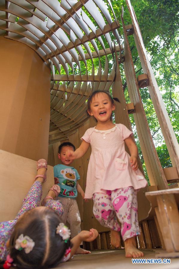 Children play in a paper house in the Chongqing University, Chongqing, southwest China, May 21, 2013. Fourteen paper houses, made up with recycled paper by more than 200 freshmen, were displayed in the Faculty of Architecture and Urban Planning of the university on Tuesday. (Xinhua/Chen Cheng)