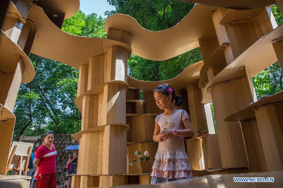 People visit a paper house in the Chongqing University, Chongqing, southwest China, May 21, 2013. Fourteen paper houses, made up with recycled paper by more than 200 freshmen, were displayed in the Faculty of Architecture and Urban Planning of the university on Tuesday. (Xinhua/Chen Cheng)