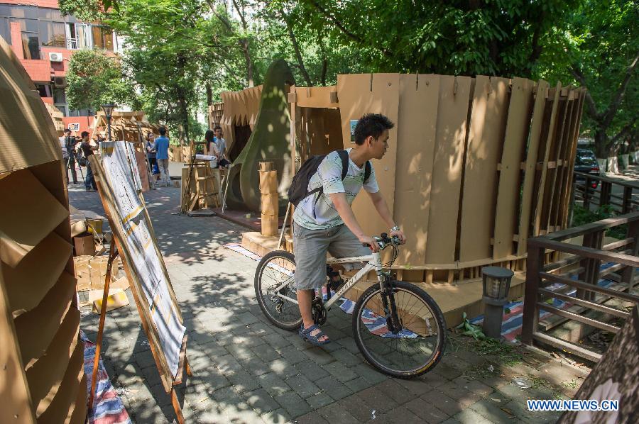 People visit paper houses in the Chongqing University, Chongqing, southwest China, May 21, 2013. Fourteen paper houses, made up with recycled paper by more than 200 freshmen, were displayed in the Faculty of Architecture and Urban Planning of the university on Tuesday. (Xinhua/Chen Cheng)