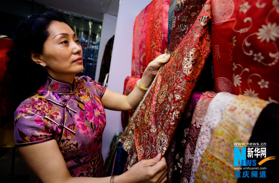 Liang Li chooses the fabric for making cheongsam in a shop in Yuzhong district in Chongqing on March 29, 2013. (Photo/Xinhua)