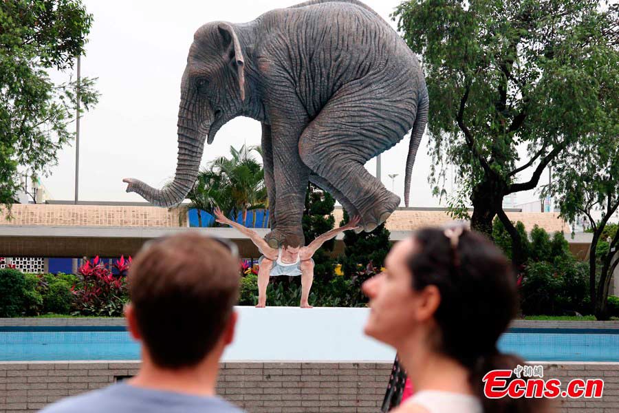  A 5-meter-high sculpture is on display in Statue Square, Hong Kong, May 21, 2013. The artwork "Pentateuque," brings to real life the fantastical and seemingly impossible act of an average man balancing a gigantic elephant, modelled on one at the Singapore Zoo, atop his back, which is actually a cast of the artist himself. [Photo: CNS/Hong Shaokui] 