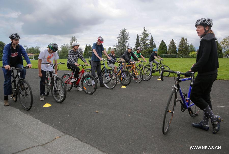 Students participate in a bike training session for the Bike to School Week at a secondary school in Vancouver, Canada, May 22, 2013. Over 40 schools from Metro Vancouver will participate in the annual Bike to School Week competition. The event aimed to educate the students to support cycling for better health, cleaner air and strong school communities. (Xinhua/Liang Sen)  