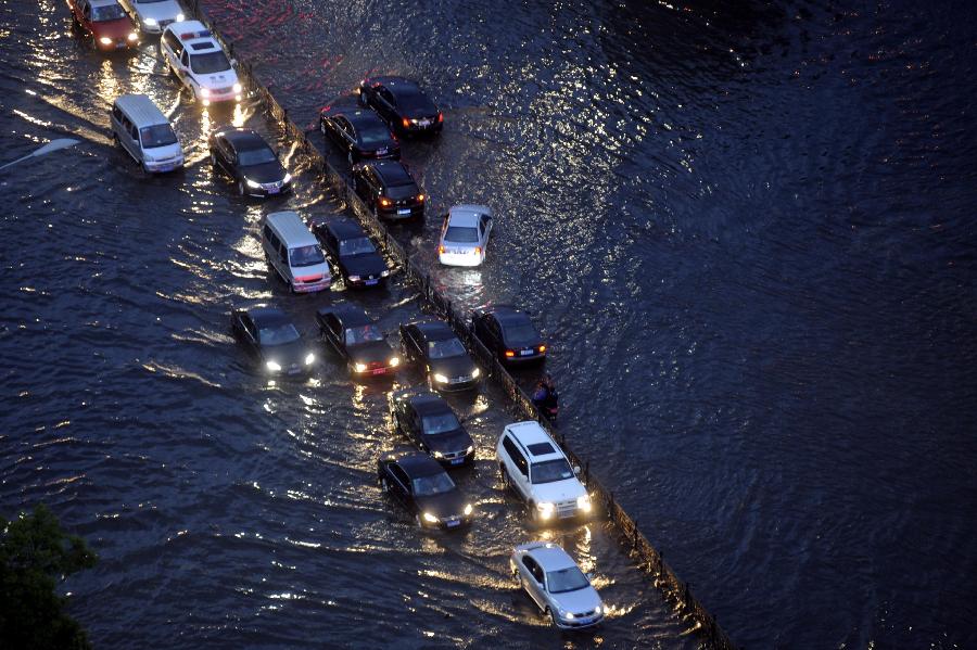 Vehicles move in the flooded-street in Taiyuan, capital of north China's Shanxi Province, May 22, 2013. Thunderstorms hit the city on Wednesday afternoon. The local meteorological authority issued a yellow warning alert against thunder at 4:15 p.m. local time. (Xinhua)