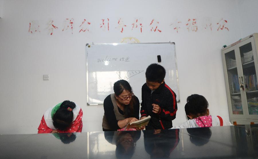 Volunteer Sun Yanfeng tutors left-behind children, whose parents go to other places to work, at an after-school care center in Yanji City, Yanbian Korean Autonomous Prefecture in northeast China's Jilin Province, May 22, 2013. More than 30,000 children are left behind by their parents who choose to go to South Korea to work in the Yanbian Korean Autonomous Prefecture. The local government established 20 after-school care centers to provide these left-behind children with the after-class care. (Xinhua/Lin Hong)