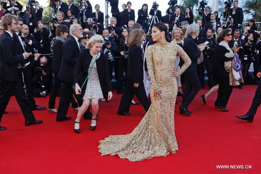 A staff member helps actress Eva Longoria as she faces the photographers while stepping on the red carpet of movie premiere during the 66th Cannes Film Festival in Cannes, France, on May 17, 2013. The film festival runs from May 15 to May 26 this year.(Xinhua/Zhou Lei) 