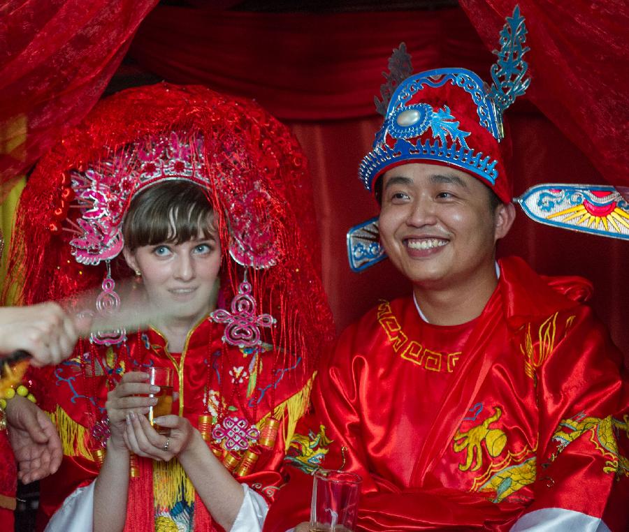 Bridegroom Zhang Lan (R) and his Russian bride Ren Niya (her Chinese name) attend the wedding ceremony in a courtyard dwelling in Chongqing, southwest China, May 23, 2013. The wedding ceremony, held in the traditional Chinese way, attracted lots of passengers to give their blessings. (Xinhua/Chen Cheng) 