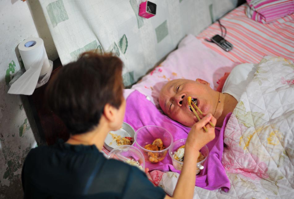 Wang Mingfang helps her husband eat lunch after a short wedding ceremony in Wuhan, Central China's Hubei province, May 21. (Photo/ Xinhua)