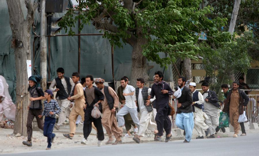 Local residents run away from the site of an attack with military vehicles in Kabul, Afghanistan on May 24, 2013. At least two suicide bombers and a policeman were killed and several others wounded on Friday evening when Taliban launched a coordinated attack in central Kabul, a police source said. (Xinhua/Ahmad Massoud)