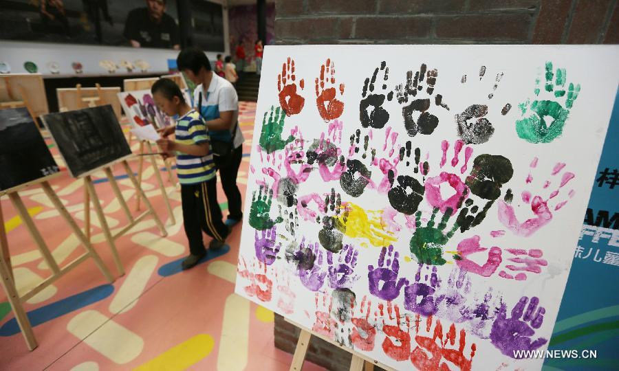 Visitors view paintings at a painting exhibition at the 798 art area in Beijing, capital of China, May 25, 2013. A two-day exhibition kicked off on Saturday, displaying paintings created by over 20 mentally retarded children from Chaoyang Anhua School. (Xinhua) 