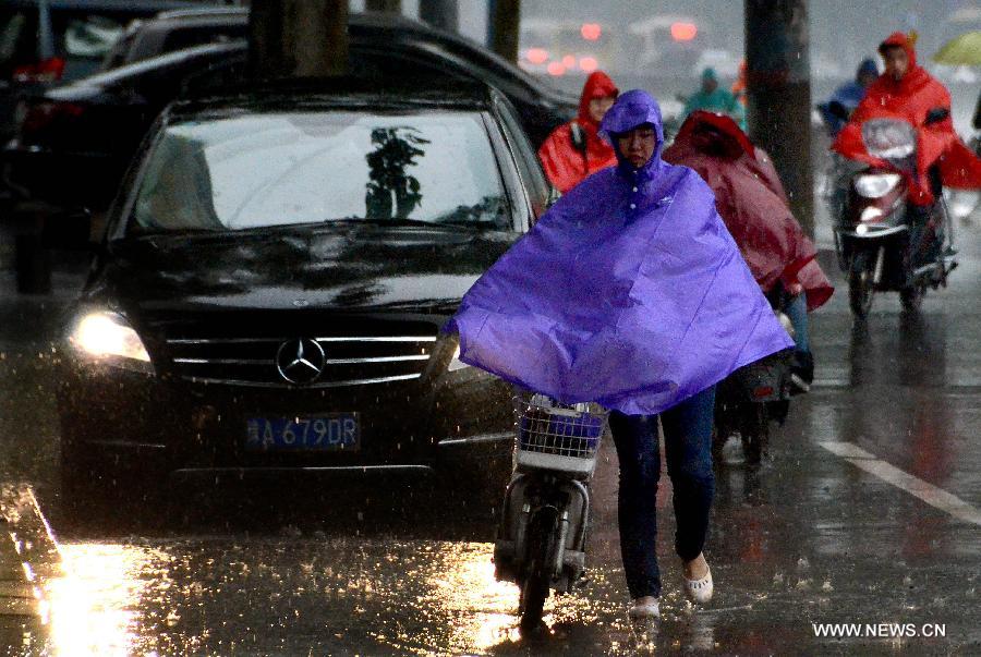 People and vehicles move on a street in rain in Zhengzhou, capital of central China's Henan Province, May 26, 2013. Many parts in Henan witnessed rainfall since Saturday. Local meteorological authorities issued a yellow alert on thunder.(Xinhua/Wang Song)