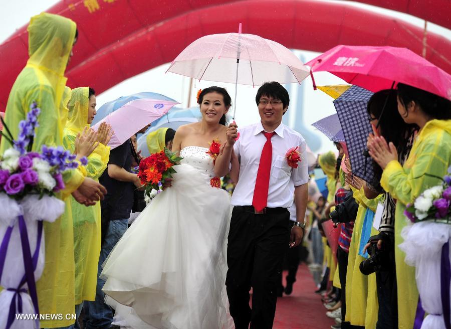 Newly-wed couples are seen at a group wedding ceremony for migrant workers in Jinan, capital of east China's Shandong Province, May 26, 2013. A group wedding was held for migrant workers here on Sunday, with 31 pairs of newly-wed couples participating. (Xinhua/Cui Jian)