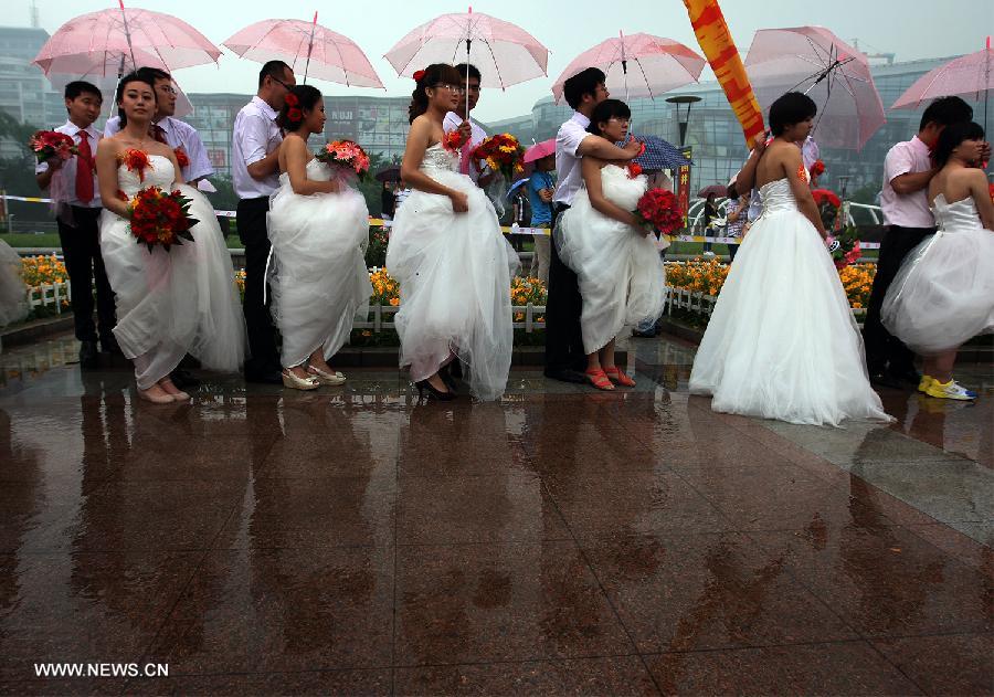 Newly-wed couples are seen at a group wedding ceremony for migrant workers in Jinan, capital of east China's Shandong Province, May 26, 2013. A group wedding was held for migrant workers here on Sunday, with 31 pairs of newly-wed couples participating. (Xinhua/Cui Jian)